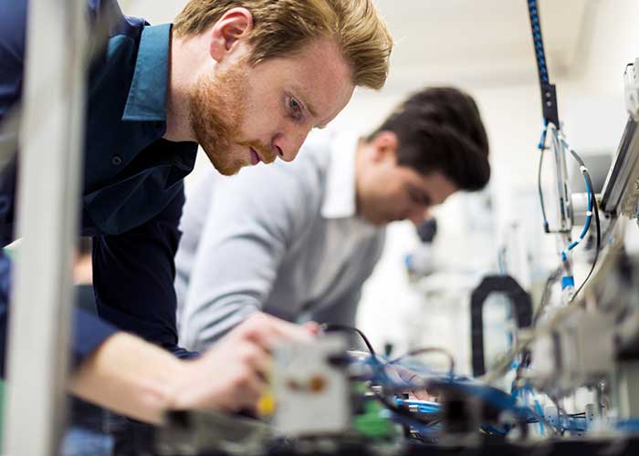 Two Young Handsome Engineers working on Electronics